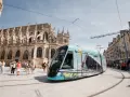 Un tram **Keolis Vélizy** décoré circule devant une cathédrale gothique. Des passants attendent sur le quai.