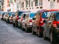 Voitures garées en file indienne sur une voie publique pavée, un **délai stationnement** qui semble long.
