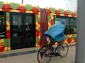 Cycliste sous la pluie, longeant un tramway décoré de fleurs colorées à Montpellier.