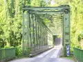 Pont métallique vert traversant une végétation luxuriante, un chemin pour le transport en commun en Martinique.