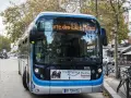 Bus Bolloré 115, direction Porte des Lilas Métro, stationné dans une rue bordée d'arbres et de commerces.