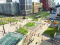 Un quartier urbain moderne avec des bâtiments hauts, des espaces verts et des gens se déplaçant à pied ou à vélo, illustrant l'innovation transport.