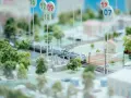 Maquette ferroviaire avec un train, des arbres et des maisons. Des panneaux indiquent des dates, peut-être pour un projet mobco 2026.