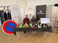 Deux hommes souriants présentent une maquette de ville et un panneau "Interdit de stationner" pour illustrer leur solution de **service voirie** connectée.