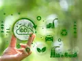 Main d'une personne tenant une sphère symbolisant la Terre et le CO2, entourée d'icônes représentant l'industrie, le transport et le recyclage, illustrant la transformation des territoires vers un avenir durable.
