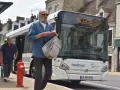 Un homme attend le bus à Nogent-le-Rotrou, sac à la main. Le panneau lumineux indique "NOBUS".
