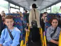 Des enfants souriants et une adulte voyagent dans un autobus scolaire aux sièges colorés.