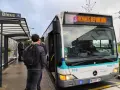 Un bus de transports urbains briochins s'arrête à un arrêt. Des passagers attendent, certains montent. Le panneau indique "53 Rennes République".