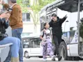 Un jeune homme et une fillette souriants marchent près d'un bus Transdev à Blois.