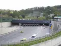 Entrée d'un **duplex autoroute** Vinci. Des voitures et des camions passent sous des portiques de péage.