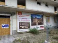 Panneau "Prochainement résidence Les terrasses fleuries" sur un bâtiment en démolition, signe de spéculation foncière.