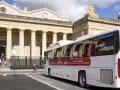 Un bus blanc "car régionaux Gironde" roule devant un bâtiment imposant avec des colonnes. Le bus arbore le slogan "Je roule au bipgaz".
