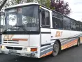 Un bus Karosa Recreo blanc avec des rayures grises et oranges, prêt pour une nouvelle aventure.