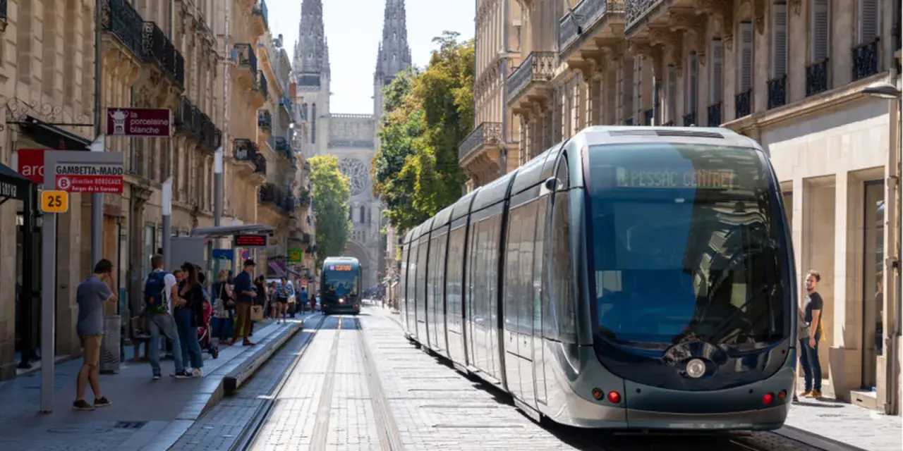 Un tramway moderne circule dans une rue pavée bordée de bâtiments anciens, témoignant du projet tramway urbain.
