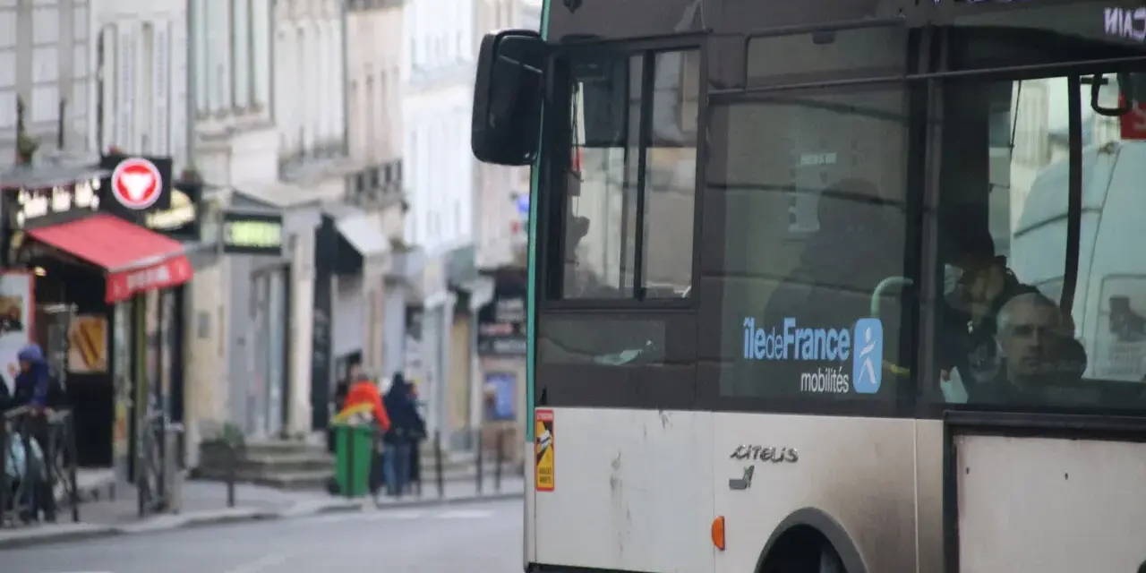 Un nouveau bus RATP, arborant le logo Île-de-France Mobilités, circule dans une rue bordée de bâtiments anciens.