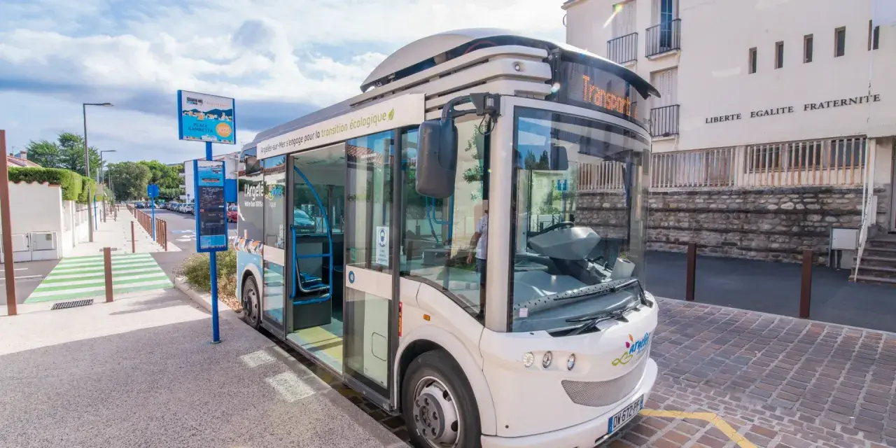 Un bus moderne, un trainbus, attend à un arrêt à Saint-Cyprien, prêt à emmener les passagers pour une transition écologique.