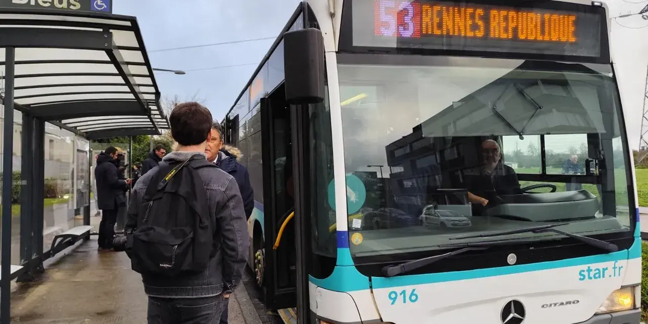 Un bus de transports urbains briochins s'arrête à un arrêt. Des passagers attendent, certains montent. Le panneau indique "53 Rennes République".