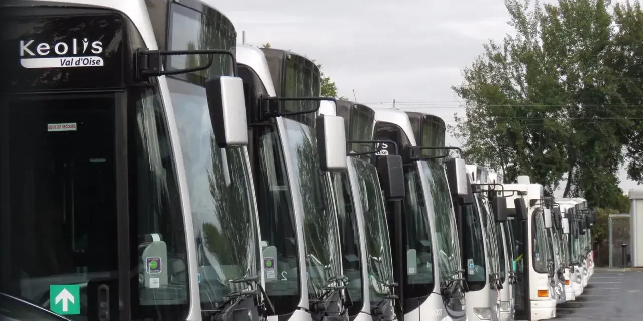 Une rangée de bus Keolis Val d'Oise stationnés, prêts pour le transport.