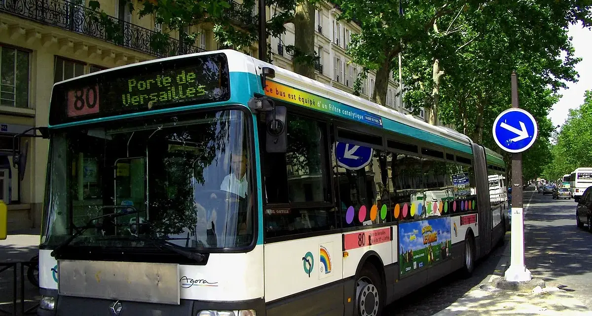 Autobus Renault Agora ligne 80, direction Porte de Versailles, circulant dans une rue bordée d'arbres à Paris.