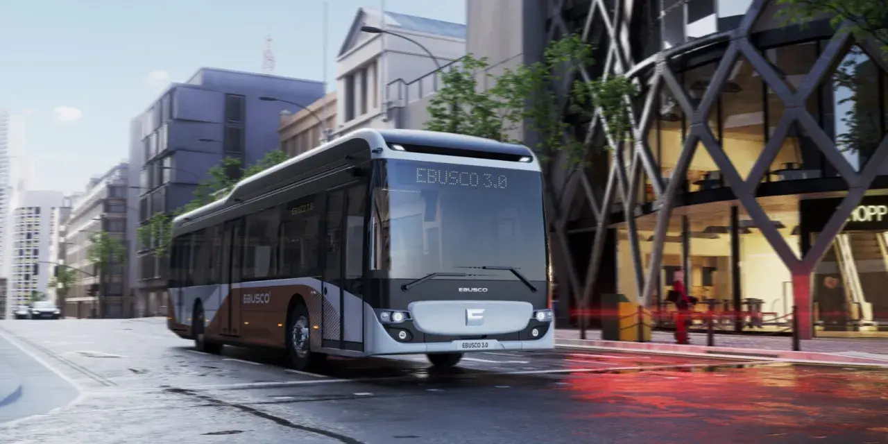 Un bus Ebusco 3.0 moderne circule dans une rue urbaine mouillée, reflétant les lumières de la ville.