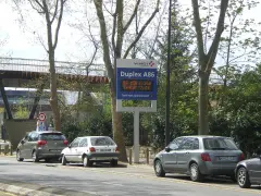 Panneau lumineux Vinci Autoroutes pour le Duplex A86, indiquant les tarifs. Des voitures sont garées sur le bord de la route.