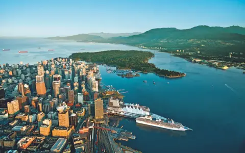 Vue aérienne de Vancouver, ville verte, avec ses gratte-ciel, son port animé et ses montagnes verdoyantes en arrière-plan.