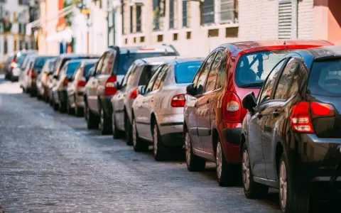 Voitures garées en file indienne sur une voie publique pavée, un **délai stationnement** qui semble long.