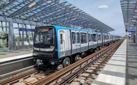 Un train de la ligne 11 du Grand Paris, direction Rosny-Bois-Perrier, s'arrête à la station Coteaux-Beauclair sous une structure moderne.