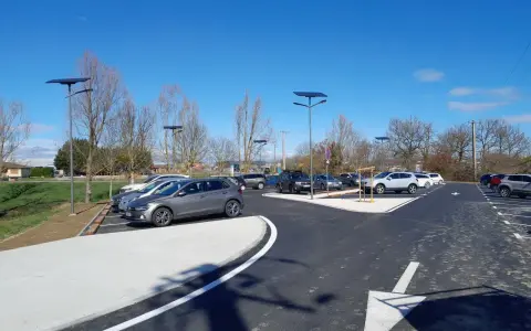 Stationnement de voitures dans une aire covoiturage Toulouse, éclairée par des lampadaires solaires sous un ciel bleu.