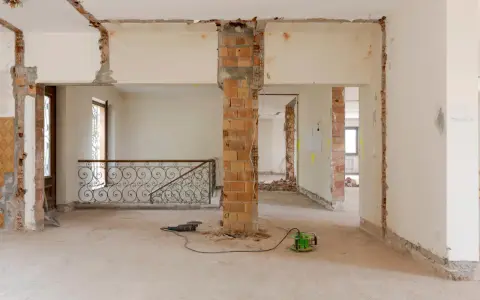 Intérieur en chantier, murs abattus, poutres apparentes. Les outils suggèrent une rénovation, pas une simple réhabilitation.