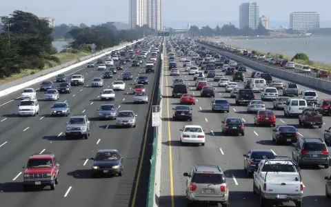 Embouteillage sur une autoroute de Los Angeles, avec des voitures sur plusieurs voies sous un ciel clair.