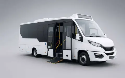 Minibus blanc avec rampe d'accès déployée, prêt à accueillir des passagers. Sa conception optimisée offre une grande capacité car pour le transport de groupe.