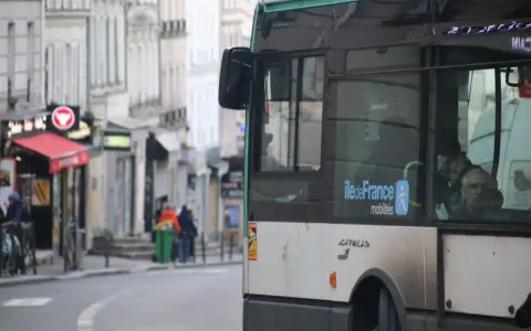 Un nouveau bus RATP, arborant le logo Île-de-France Mobilités, circule dans une rue bordée de bâtiments anciens.
