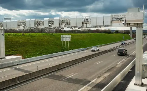 Portique de péage urbain sur une autoroute, avec des voitures passant sous les caméras.