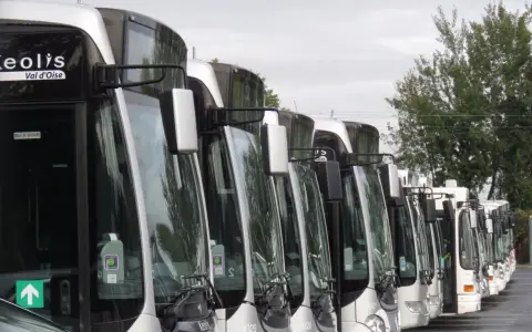 Une rangée de bus Keolis Val d'Oise stationnés, prêts pour le transport.