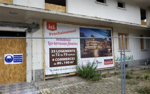 Panneau "Prochainement résidence Les terrasses fleuries" sur un bâtiment en démolition, signe de spéculation foncière.