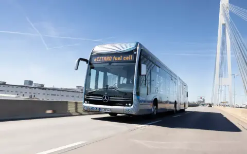 eCitaro fuel cell, un bus articulé futuriste, roule sur une autoroute sous un ciel bleu. Sa fiche technique promet une mobilité propre.