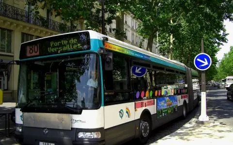 Autobus Renault Agora ligne 80, direction Porte de Versailles, circulant dans une rue bordée d'arbres à Paris.