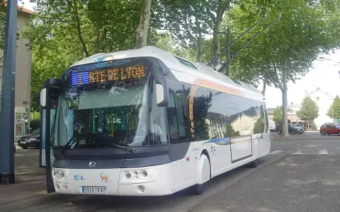 Trolleybus blanc à Lyon, prêt à partir. Les perches électriques sont visibles sur le toit.