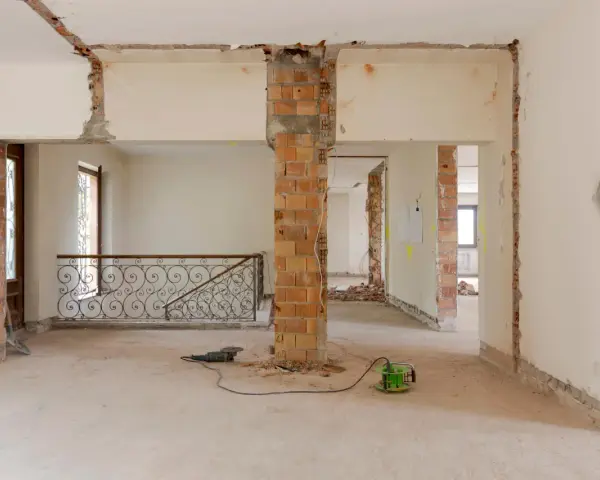 Intérieur en chantier, murs abattus, poutres apparentes. Les outils suggèrent une rénovation, pas une simple réhabilitation.