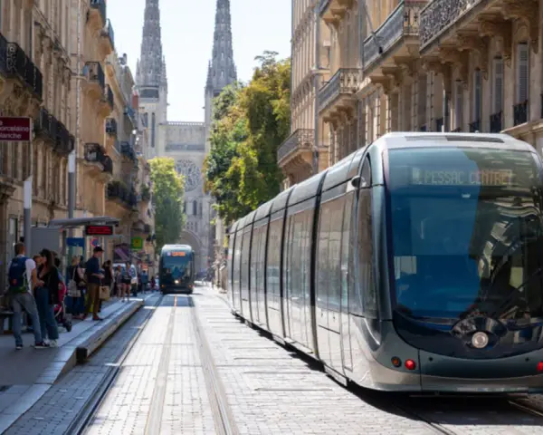 Un tramway moderne circule dans une rue pavée bordée de bâtiments anciens, témoignant du projet tramway urbain.