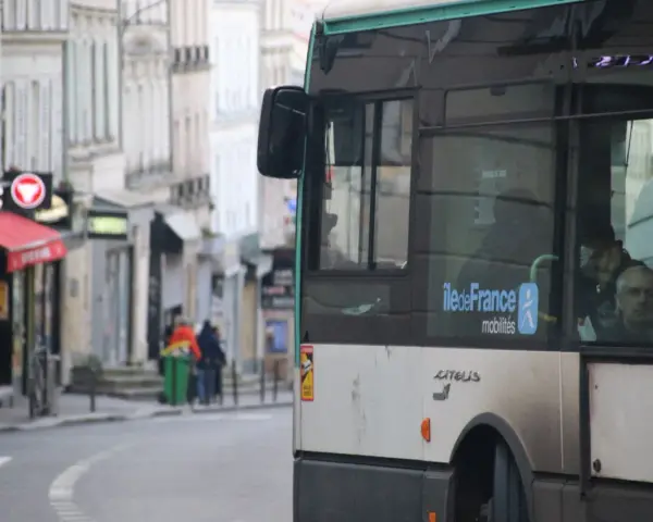 Un nouveau bus RATP, arborant le logo Île-de-France Mobilités, circule dans une rue bordée de bâtiments anciens.