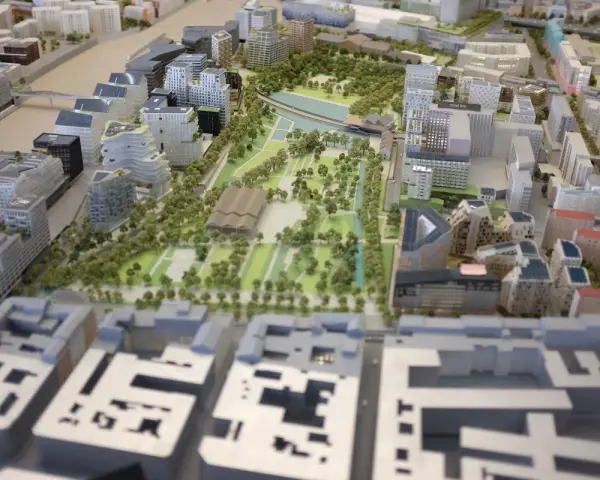 Maquette d'une ville moderne avec des bâtiments aux formes variées, des espaces verts et un plan d'eau. Une vision de la planification urbaine.