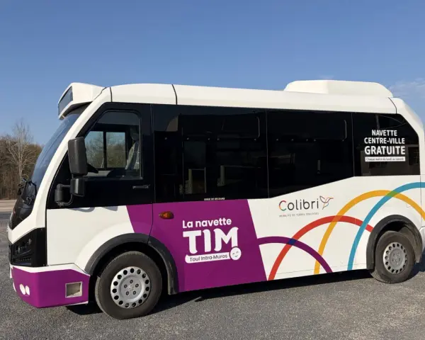 Le bus TIM, navette gratuite de Toul Intra-Muros, roule sous un ciel bleu.