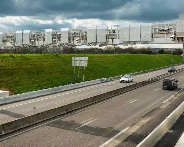 Portique de péage urbain sur une autoroute, avec des voitures passant sous les caméras.