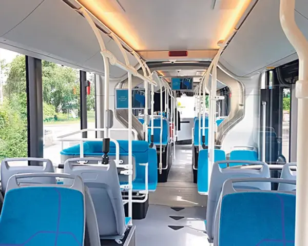 Intérieur d'un bus IDFM moderne avec des sièges bleus et gris, des barres de maintien et de grandes fenêtres donnant sur la verdure.