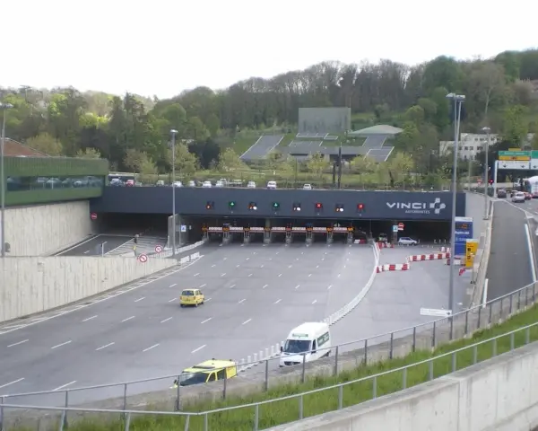 Entrée d'un **duplex autoroute** Vinci. Des voitures et des camions passent sous des portiques de péage.