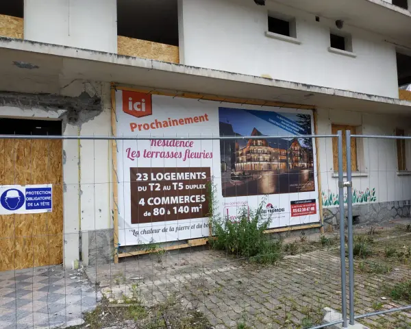 Panneau "Prochainement résidence Les terrasses fleuries" sur un bâtiment en démolition, signe de spéculation foncière.