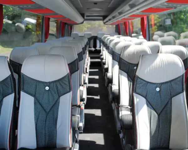 Intérieur d'un tour bus avec des sièges confortables et des rideaux rouges.