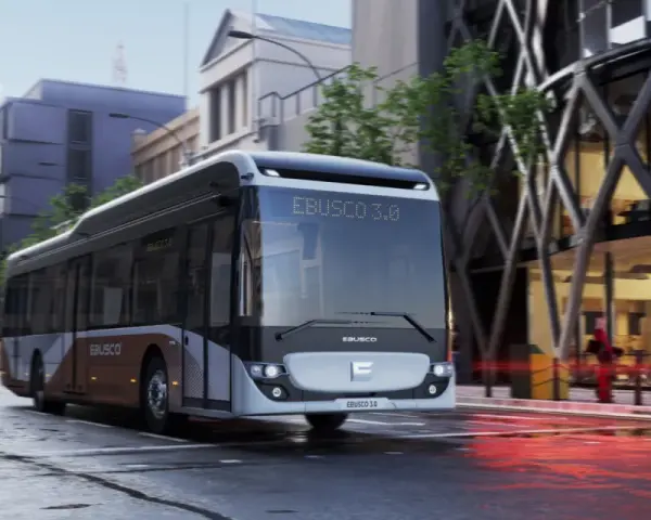 Un bus Ebusco 3.0 moderne circule dans une rue urbaine mouillée, reflétant les lumières de la ville.